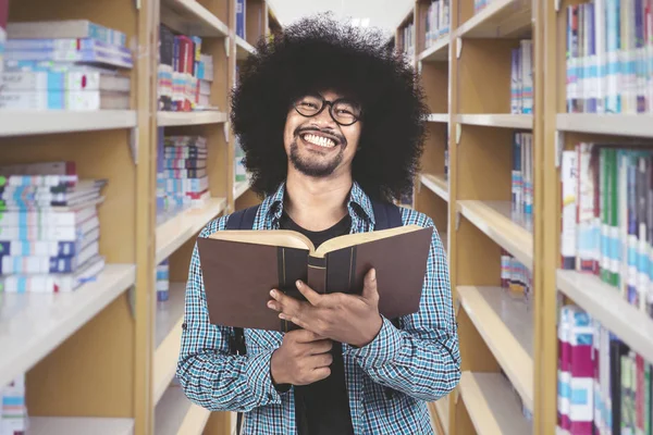 Africký muž držící knihu v knihovně — Stock fotografie