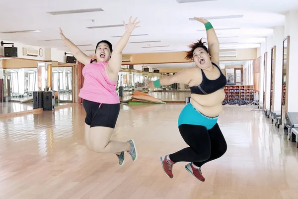 Dos mujeres felices con sobrepeso saltando juntas — Foto de Stock