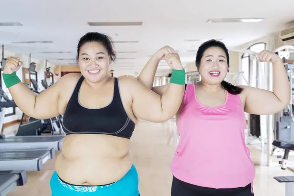 Dwie kobiety tłuszczu pokazano ich mięśni ramienia — Zdjęcie stockowe