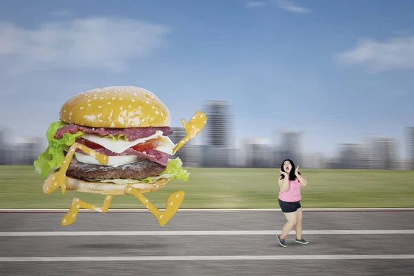 Przestraszony otyła kobieta ucieka z hamburger — Zdjęcie stockowe