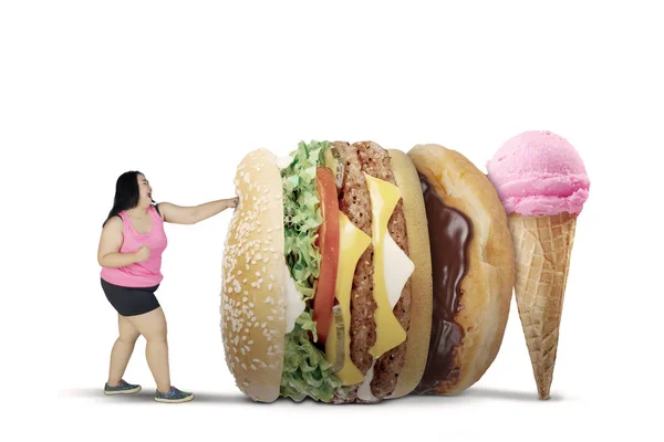 Fettleibige Frau kämpft im Studio mit ungesunden Lebensmitteln — Stockfoto