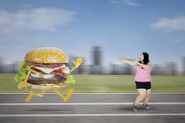 Gruba kobieta uciekając z burger — Zdjęcie stockowe