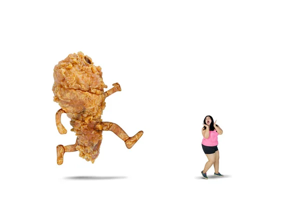 Fat woman chased by a fried chicken on studio — Stock Photo, Image
