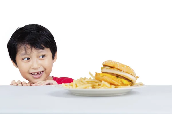 Söt liten pojke kika välsmakande hamburgare — Stockfoto