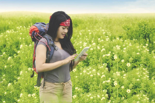 Beautiful backpacker with smartphone in flower field — Stock Photo, Image