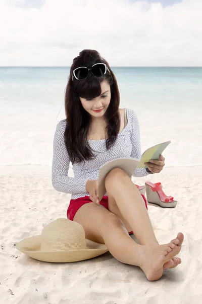 Азиатка читает книгу на пляже — стоковое фото