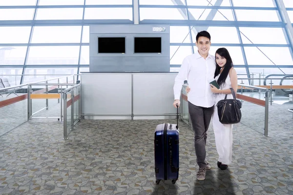 Casal asiático com mala abraçando em um terminal de aeroporto — Fotografia de Stock