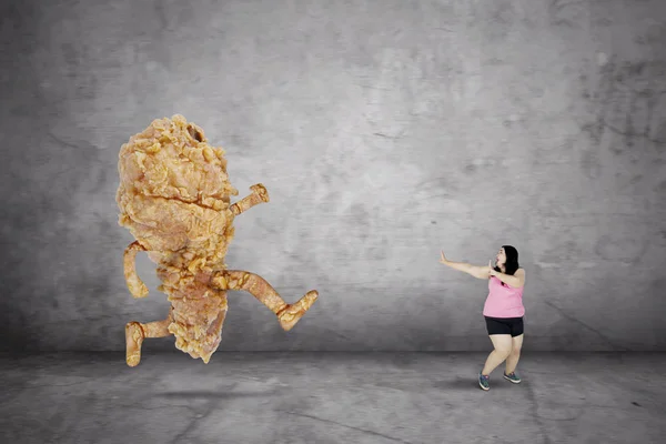 Mulher com excesso de peso escapando de um frango frito — Fotografia de Stock