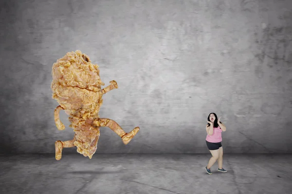 Παχύσαρκη γυναίκα κοιτάζει φοβισμένο με ένα τηγανητό κοτόπουλο — Φωτογραφία Αρχείου