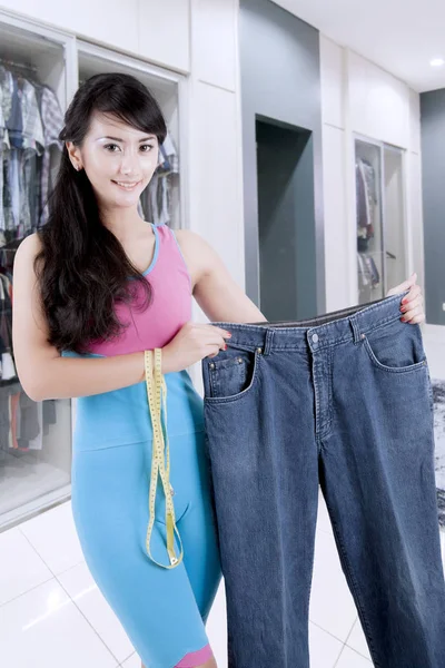 Schöne schlanke asiatische Frau zeigt ihre übergroßen alten Jeans — Stockfoto