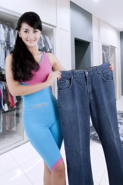 Slimming woman holding an oversized jeans — Stock Photo, Image