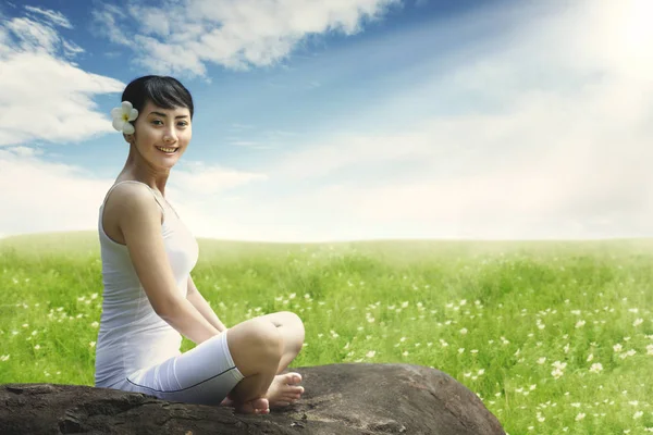 Asiatique femme profiter de plein air assis sur la roche à prairie contre ciel bleu — Photo