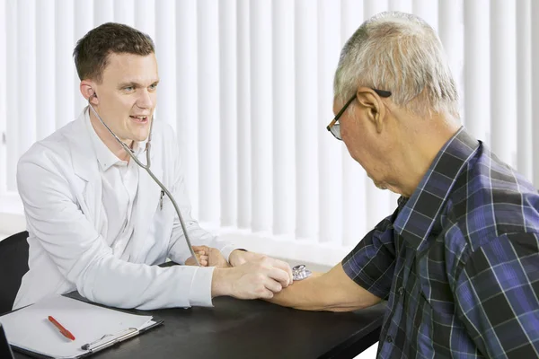 Médico americano examina homens idosos batimentos cardíacos — Fotografia de Stock