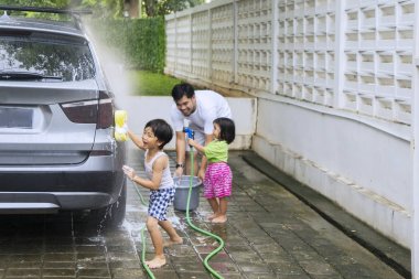İki küçük çocuk babaları birlikte bir araba yıkarken yardım resmi