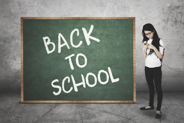 Student with cellphone and chalkboard — Stock Photo, Image