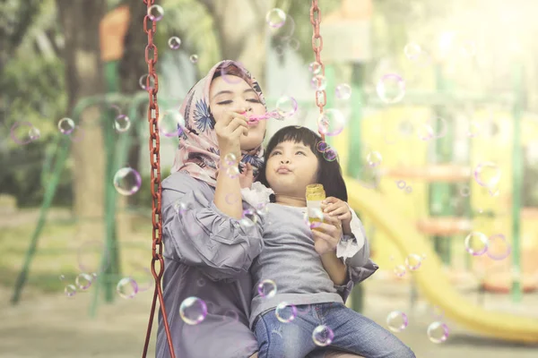 穆斯林妇女与孩子吹肥皂气泡 — 图库照片