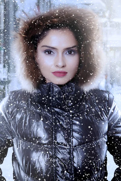 Indian woman wearing a winter jacket under snowfall — Stock Photo, Image