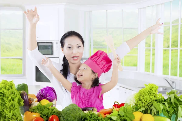 Девочка и мама с овощами на кухне — стоковое фото