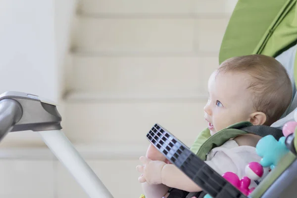 Baby girl looks happy while sitting in the stroller — Stock Photo, Image