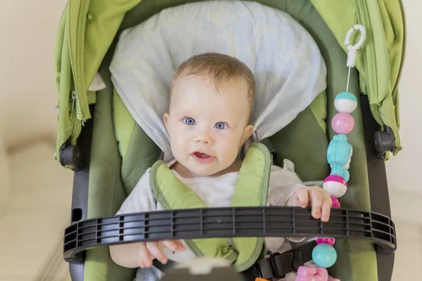 Mooi baby meisje zitten in de wandelwagen — Stockfoto