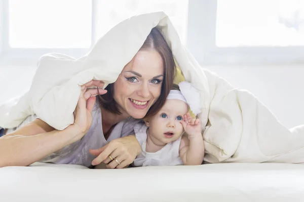 Blanke vrouw en haar baby onder een deken — Stockfoto
