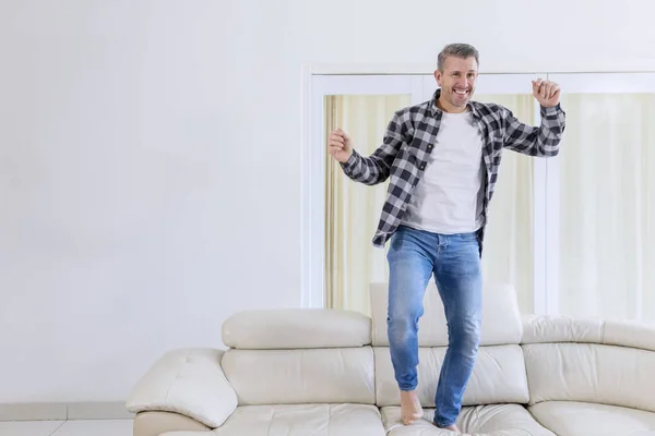 Fröhlicher Mann tanzt auf der Couch — Stockfoto