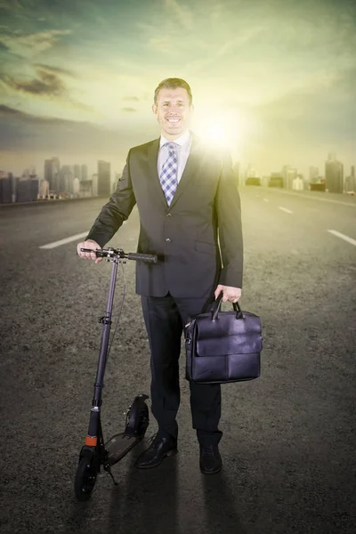 Feliz hombre de negocios de pie con una patada scooter — Foto de Stock