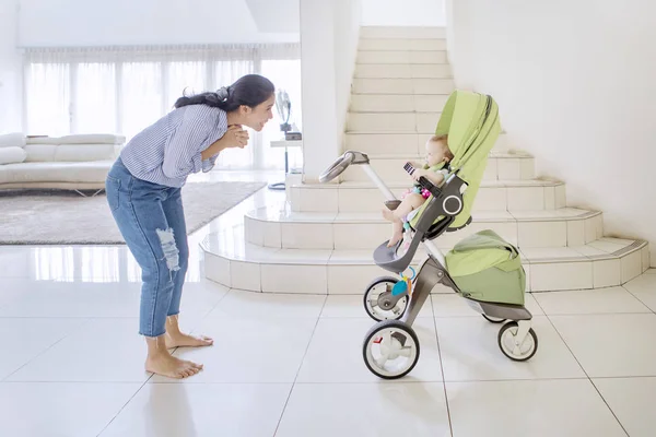 Donna felice gioca con il suo bambino in un passeggino — Foto Stock