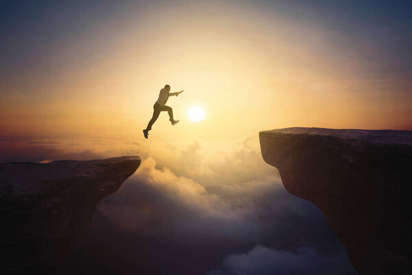 Male entrepreneur jumps through gap cliff