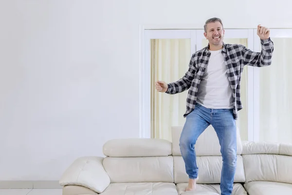 Uomo che balla sul divano con espressioni felici — Foto Stock