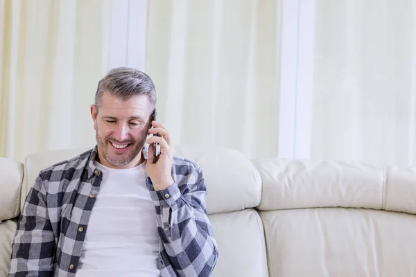 Muž vypadá šťastně, když mluví po telefonu doma — Stock fotografie