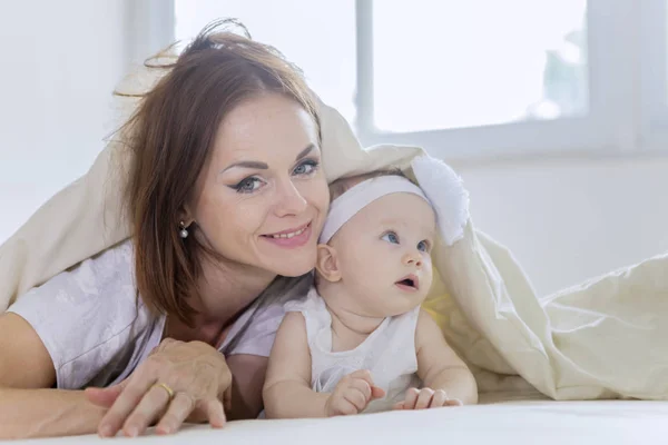 Frau spielt mit ihrem Baby unter einer Decke — Stockfoto