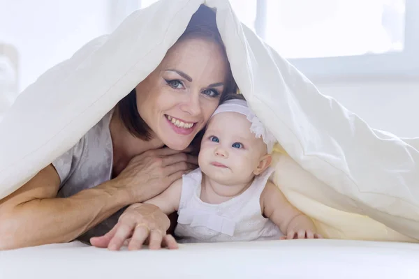 Young mother plays with her baby under a blanket — Stock Photo, Image