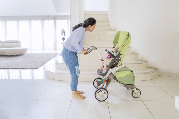 Giovane donna che ride con il suo bambino in un passeggino — Foto Stock