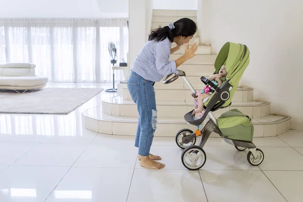 Jonge vrouw spelen met haar baby in een wandelwagen — Stockfoto