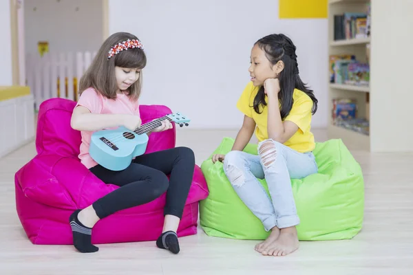 Menina caucasiana ensinando seu amigo a tocar guitarra — Fotografia de Stock