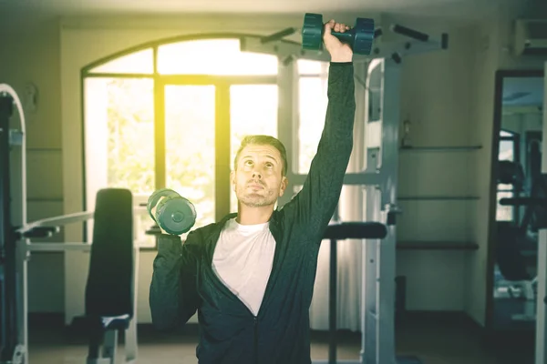 Caucasian man exercises with dumbbells at indoors — Stock Photo, Image
