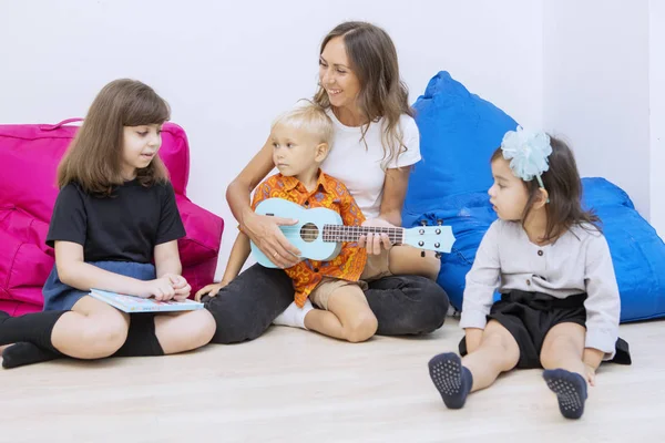 Вчителька грає на гітарі з групою дітей — стокове фото