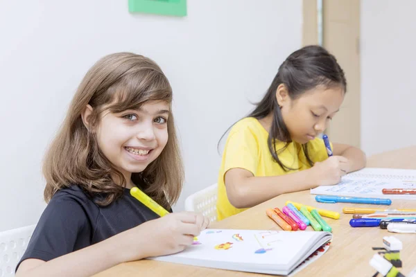 Joyeux petite fille étudiant avec son ami dans la classe — Photo