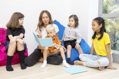 Anaokulu öğretmeni çocuklara masal kitabı okur.