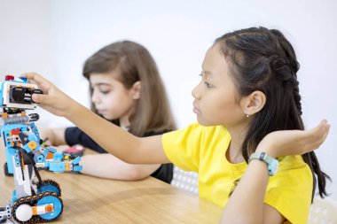 İki küçük kız sınıfta bir Lego robotu yapıyor.
