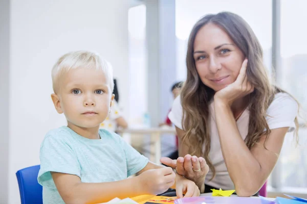 Petit garçon et professeur collant des bibelots à la maternelle — Photo