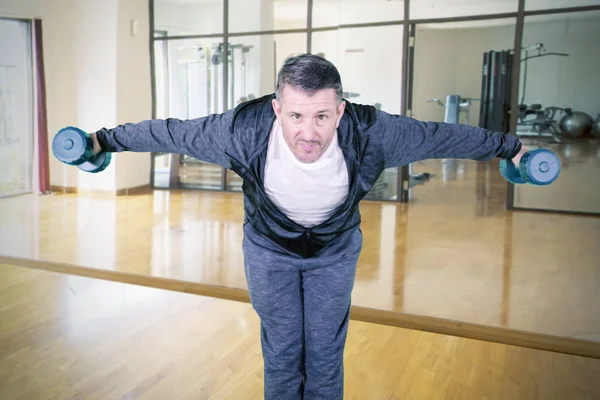 Man doing exercises with dumbbells in gym center — ストック写真