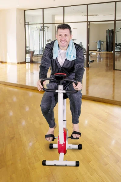 Man exercising on a spin bike in fitness center — ストック写真