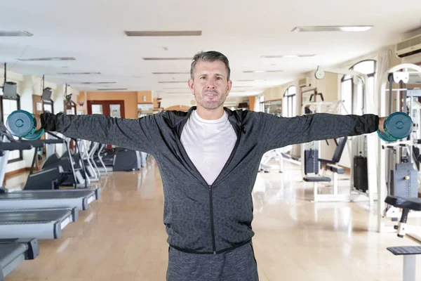 Mature man trains with dumbbells in gym center — ストック写真