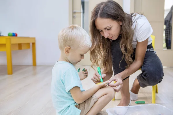 Moeder kleuren palmen van haar zoon met krijtjes — Stockfoto