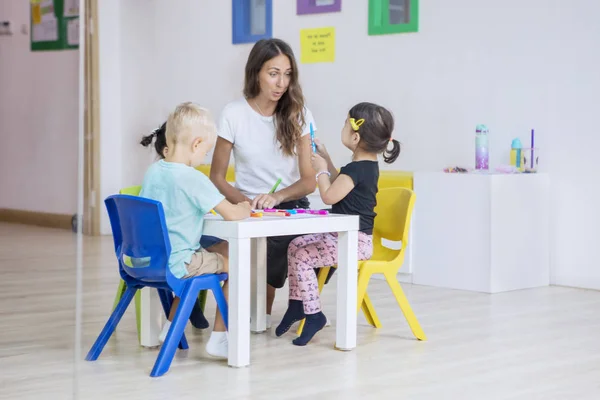 Vorschulkinder malen mit ihrer Lehrerin am Tisch — Stockfoto