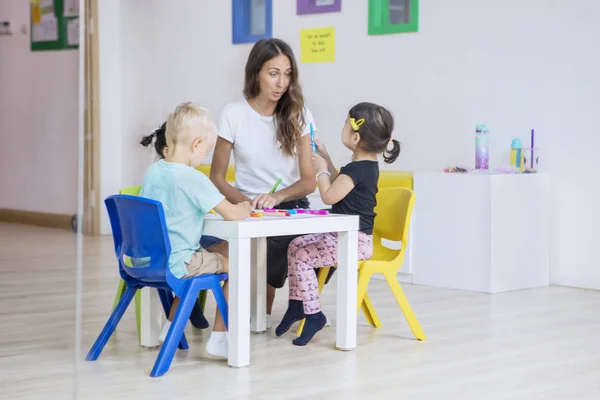 Les enfants d'âge préscolaire dessinent sur la table avec leur professeur — Photo