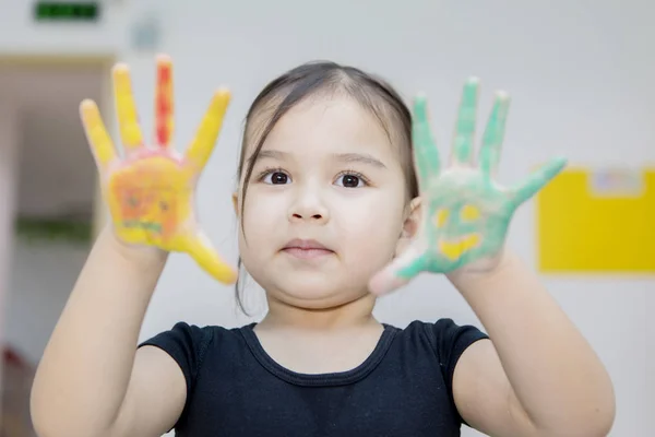 Adorable girl shows painted hands at the camera — ストック写真