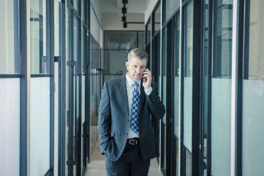 Kafkas işadamı koridorda cep telefonu kullanıyor.